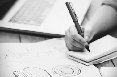 A person writes on paper with a pen, focusing intently on their task.